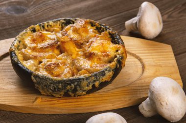 Tahta masada tavada peynir hamuruyla pişirilmiş mantarlar.