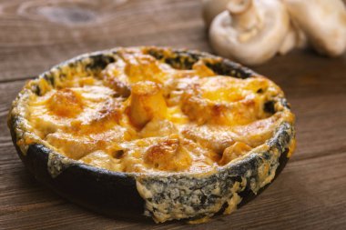 Tahta masada tavada peynir hamuruyla pişirilmiş mantarlar.