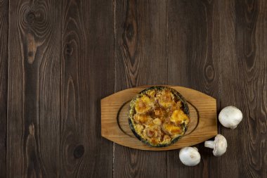 Tahta masa üzerinde peynir hamuruyla pişirilmiş mantarlar.