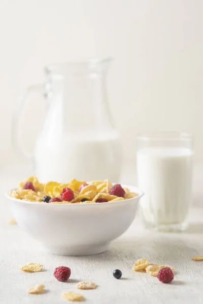 Healthy breakfast with cereal and blueberry and raspberry.Bowl with healthy cornflakes, milk and berries on white table.Tasty circle cornflakes.oatmeal with fruits. Diet concept.