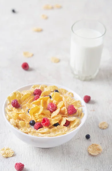 Tasty corn flakes with raspberries and blueberries on white background.Breakfast. Cornflakes with berry and milk. Cereal flakes. Fresh healthy food. Morning meal. Wooden table. Organic. Diet concept.