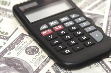 Birkaç dolar ve masa üzerinde bir hesap makinesi, finans ve tasarruf. İş konsepti