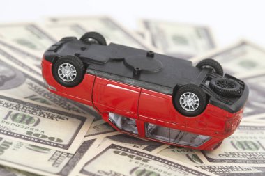 Oyuncak, kırmızı araba dolar banknotlarında kaza geçirdi. Sigorta konsepti.