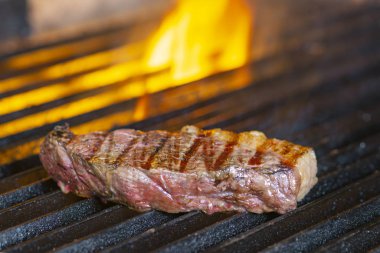 Izgarada alevler içinde biftek cızırdıyor.