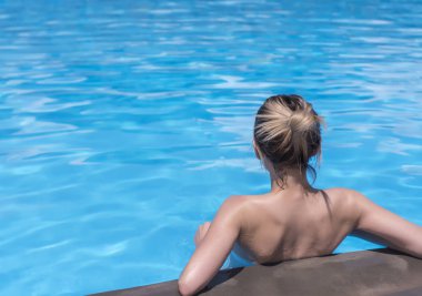 Güneşli bir günde havuzda dinlenen güzel genç bir kadın.