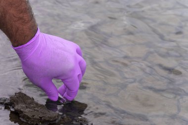 Nehirden bir su örneği. Eldiven takıp test tüpünde su topluyor. ekoloji kavramı