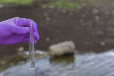 Analiz için nehirden örnek su. Bir test tüpü tutan eldiven. Ekoloji konsepti.