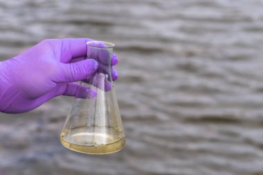 Analiz için nehirden örnek su. Bir test tüpü tutan eldiven. Ekoloji konsepti.