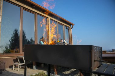 Portatif bir barbekü merkezinde küçük odun parçaları üzerinde yanan odun kütükleri ile taze yakılmış barbekü ateşi.