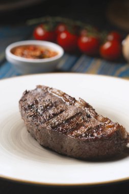 Izgara biftek, kiraz domatesleri ahşap masada tuz ve biber..