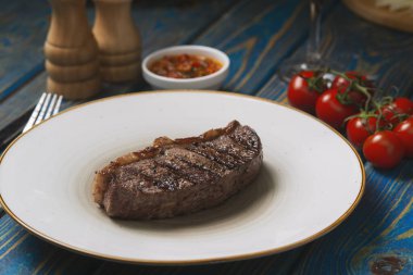 Izgara biftek, kiraz domatesleri ahşap masada tuz ve biber..