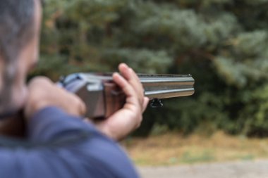 Erkek avcı av tüfeğiyle avlanmaya hazır. Avcı tüfeğini tutuyor..