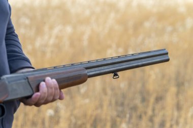 Erkek avcı av tüfeğiyle avlanmaya hazır. Avcı tüfeğini tutuyor..