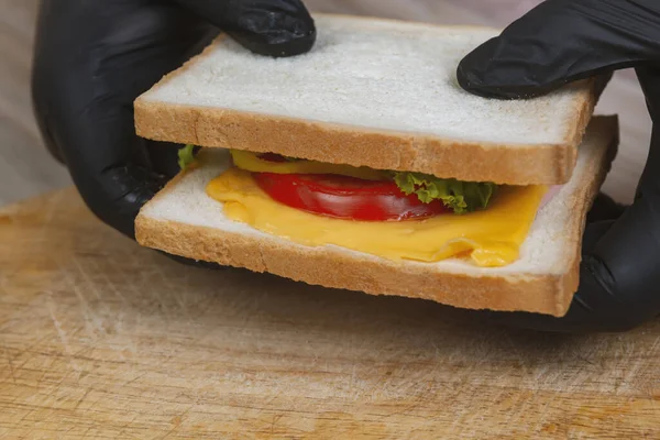 Man Black Gloves Prepare Sandwich Wooden Desk — Stock Photo, Image