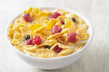 Bir kase mısır gevreği, sütlü, taze ahududu, yabanmersini. Sağlıklı kahvaltı için, kapatın.