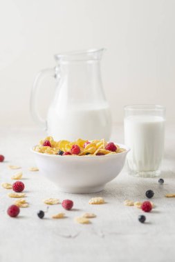 Böğürtlenli mısır gevreği, yabanmersini ve beyaz ahşap arka planda sütlü frenk üzümü.