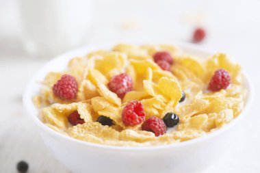 Bir kase mısır gevreği, sütlü, taze ahududu, yabanmersini. Sağlıklı kahvaltı için, kapatın.