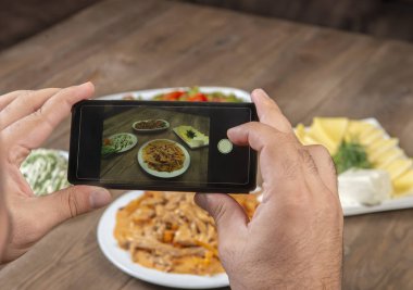 Yemek blogcusu akıllı telefon kullanarak fotoğraf çekiyor. Mans elleri geleneksel yemeklerin fotoğrafını çekiyor. Öğle ya da akşam yemeği. Sığır stroganoff. Sosyal medya ve blog için. Üst görünüm cep telefonu.