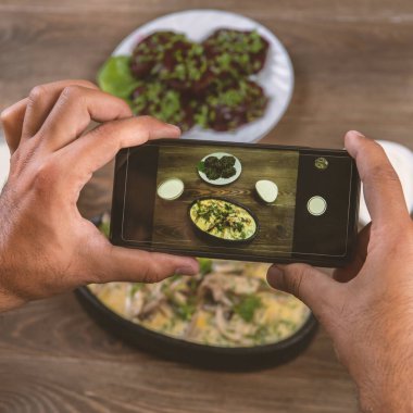 Gıda blogger fotoğraf çekmek akıllı telefon kullanarak . Mans eller Oryantal geleneksel yemekler telefon fotoğrafçılığı yapmak. öğle veya akşam yemeği. Sosyal medya için, bloglama.