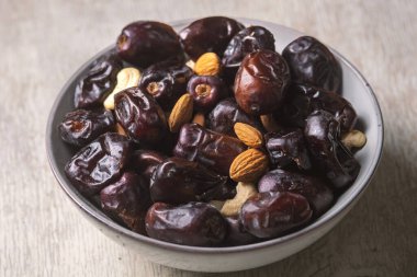Beyaz ahşap arka planda fındık ve hurma karışımı sağlıklı yiyecekler.