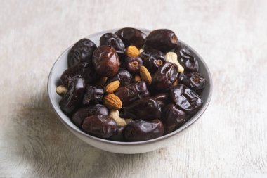 Beyaz ahşap arka planda fındık ve hurma karışımı sağlıklı yiyecekler.