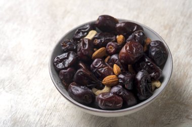 Beyaz ahşap arka planda fındık ve hurma karışımı sağlıklı yiyecekler.