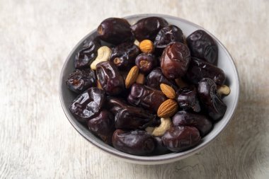 Beyaz ahşap arka planda fındık ve hurma karışımı sağlıklı yiyecekler.