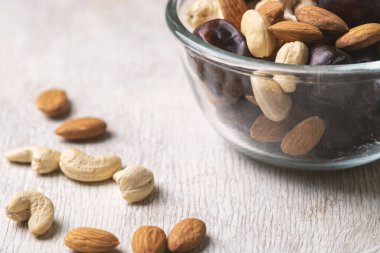 Beyaz ahşap arka planda fındık ve hurma karışımı sağlıklı yiyecekler.