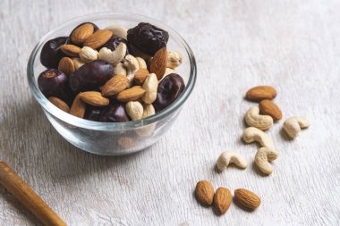 Beyaz ahşap arka planda fındık ve hurma karışımı sağlıklı yiyecekler.