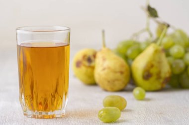 Beyaz ahşap zemin üzerinde armutlar, üzümler ve meyve suyu