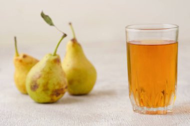 Beyaz ahşap arka planda bir bardakta armut suyu.