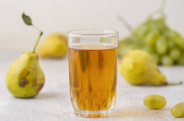 Beyaz ahşap arka planda bir bardak armut ve üzüm suyu.