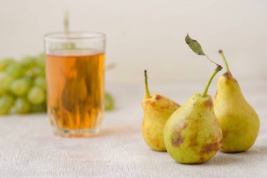 Beyaz ahşap zemin üzerinde armutlar, üzümler ve meyve suyu