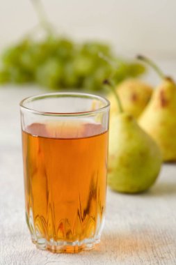 Beyaz ahşap arka planda bir bardak armut ve üzüm suyu.