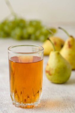 Beyaz ahşap arka planda bir bardak armut ve üzüm suyu.