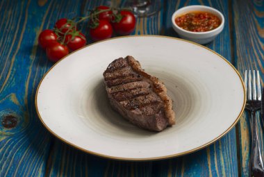Izgara biftek, kiraz domatesleri ahşap masada tuz ve biber..