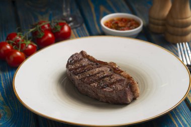 Izgara biftek, kiraz domatesleri ahşap masada tuz ve biber..