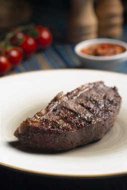 Izgara biftek, kiraz domatesleri ahşap masada tuz ve biber..