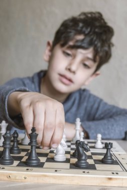 Sevimli küçük çocuk evde satranç oynuyor.
