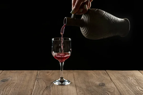 Руки Девушки Наливают Красное Вино Бокал Глиняной Бутылки Черном Фоне — стоковое фото