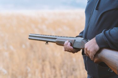 Erkek avcı av tüfeğiyle avlanmaya hazır. Avcı tüfeğini tutuyor..