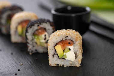 Pilavlı suşi, salatalık, avokado, somon, susam. Suşi menüsü. Japon yemeği..