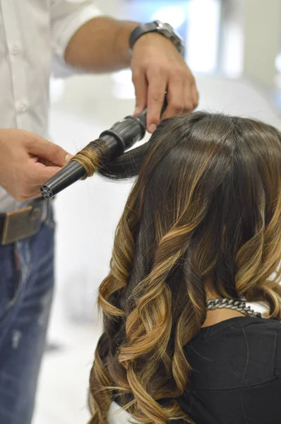 hair dresser making curls for woman