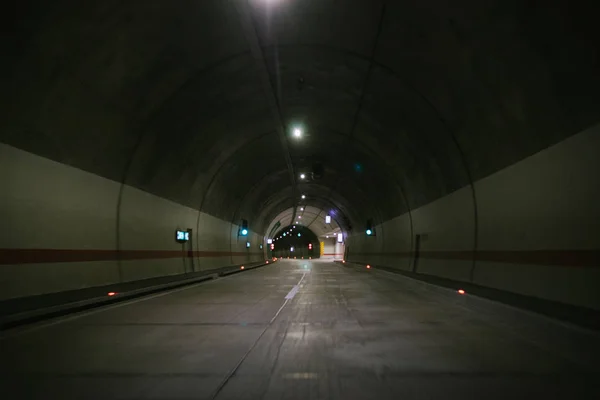 empty asphalt road in dark tunnel with light