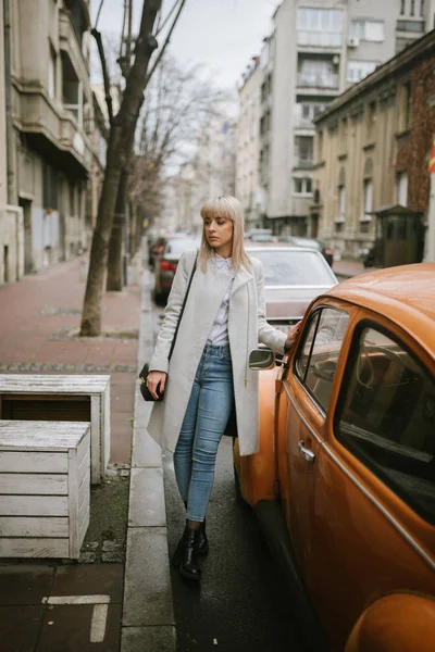 full length of beautiful blonde woman walking on autumn city street