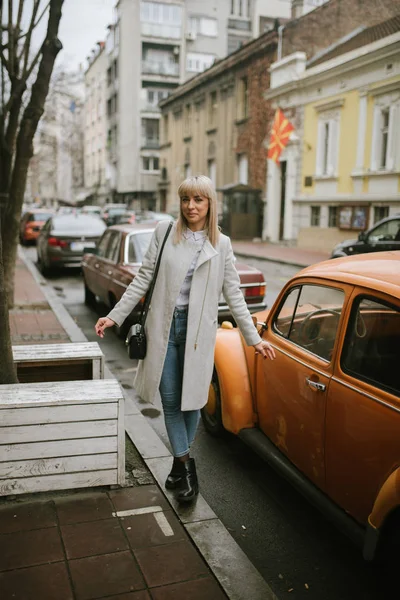 full length of beautiful blonde woman walking on autumn city street