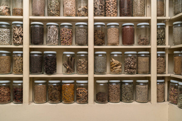 Glass bottles with colorful spices on the shelfs