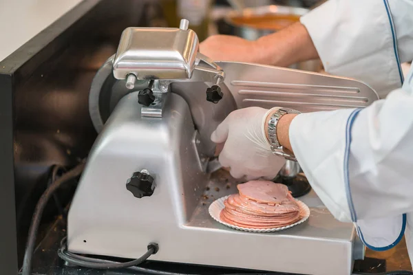 Chef che indossa guanto di gomma utilizzando la macchina affettatrice di prosciutto — Foto Stock