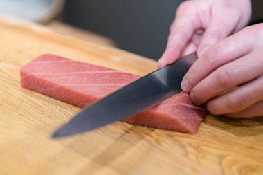 Şef bir kesme tahtası üzerinde taze ton balıklı otoro suşi için hazırlanıyor
