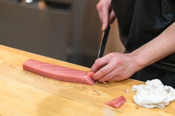 Chef préparant un thon frais sur une planche à découper pour otoro sushi — Photo